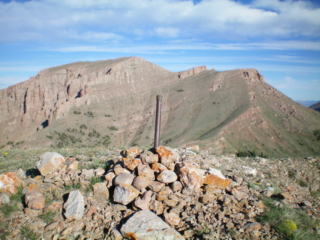 The summit cairn and ID/MT boundary post atop Knob Mountain. The Red Conglomerate Peaks are in the background. Livingston Douglas Photo