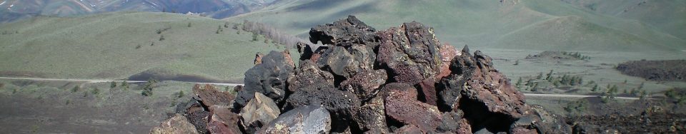 The large summit cairn atop the high point of North Crater in Craters of the Moon National Monument. Snow-clad Blizzard Mountain is in the distance. Livingston Douglas Photo