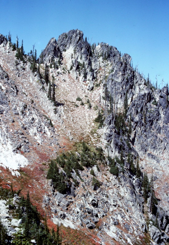 The route up Chimney Peak cuts diagonally up the steep meadow from bottom left to the right side of the photo's high point.